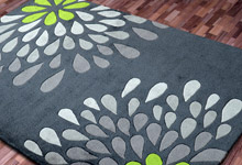 Zielony dywan akrylowy z wzorem w kolorach bladego błękitu i fioletu - łezkowate płatki układające się w kwiat 